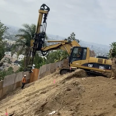 A drill rig boring into a hillside lot