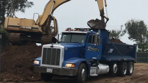 An excavator loading soil into a dump truck