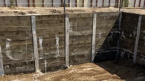 Timber lagging and steel soldier piles holding back the side of an excavation